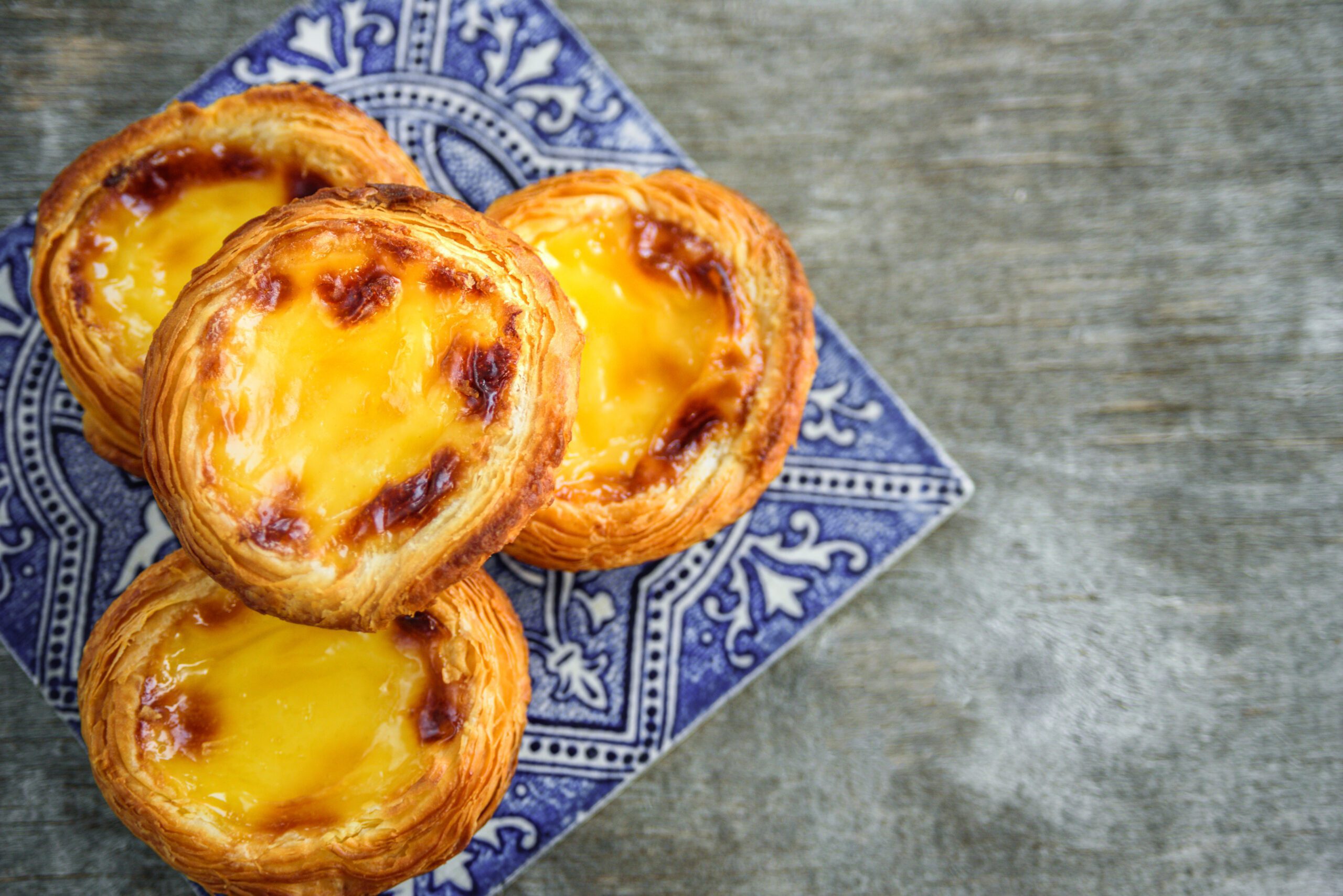 4 pasteis de nata on traditional calcada pavement