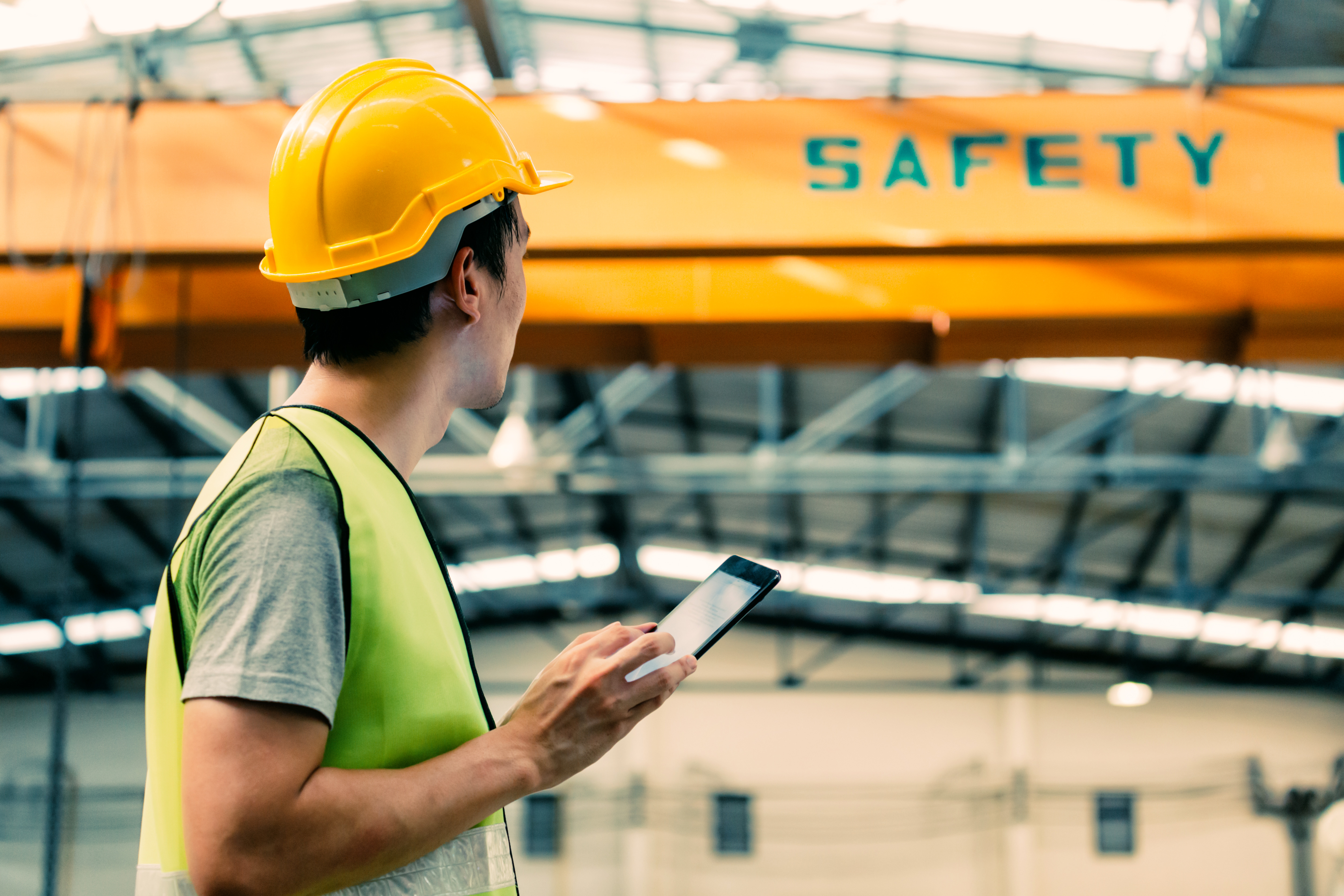A technician in industry hall holding a tablet