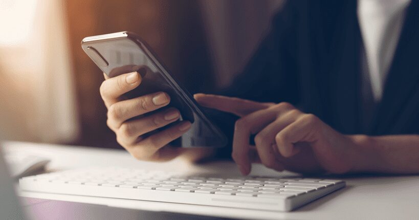 keyboard and hands holding a phone