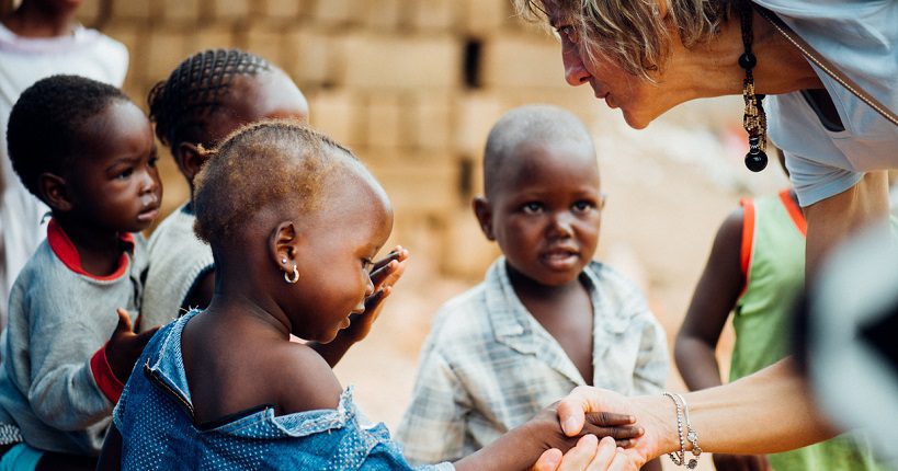 Humanitarian worker from NGO greeting children in Africa