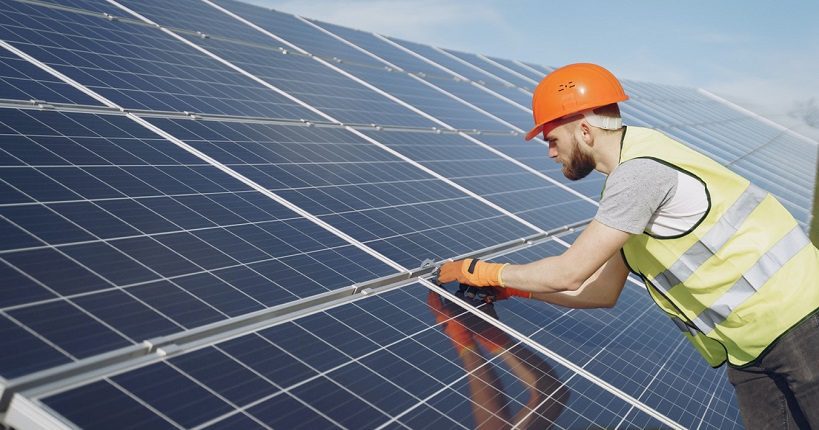 a technician installing solar panel in solar farm